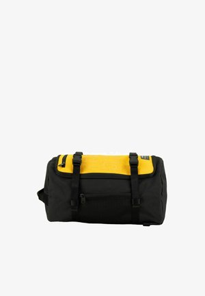Schwarz-gelbe Reisetasche mit vorderer Netztasche, zwei schwarzen Schnallenriemen oben und kleinem Reißverschlussfach auf der gelben Klappe.