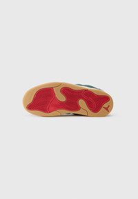 Talpa de sneaker din cauciuc cu un model de tracțiune ondulat de culoare roșie. Prezentând o margine maronie și detalii de branding, structură întărită și suprafață texturată.