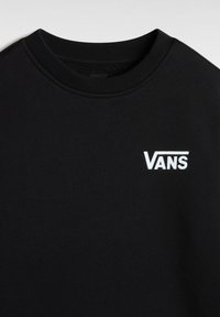 T-shirt noir à col rond avec logo Vans blanc imprimé sur le côté gauche de la poitrine, design simple, texture de tissu en coton visible.