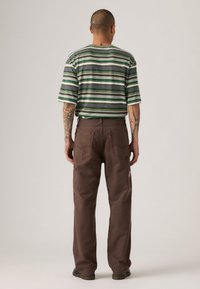 Chemise à manches courtes rayée verte et grise avec une coupe décontractée, associée à un pantalon cargo marron avec des poches latérales et un design décontracté.