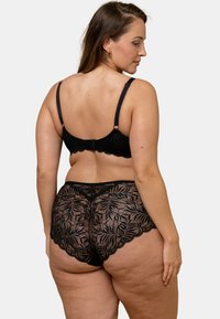 Ensemble de lingerie en dentelle noire avec un motif floral. Le soutien-gorge a des bretelles réglables et une fermeture à crochets ; le slip est taille haute avec des bords festonnés.