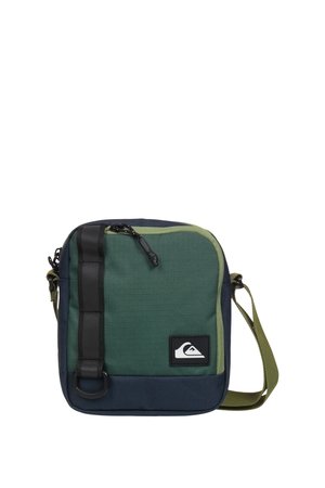 Petit sac carré bandoulière en tissu vert et marine avec fermeture éclair noire et bandoulière verte réglable.