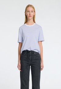 Randig T-shirt i ljusblått och vitt, i bomullsmaterial, med rund halsringning och korta ärmar. Sammanfogas med högmidjade svarta denimjeans.