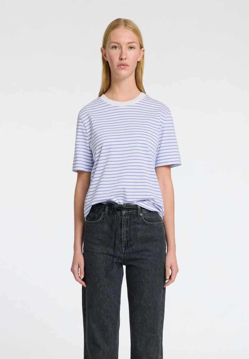 Randig T-shirt i ljusblått och vitt, i bomullsmaterial, med rund halsringning och korta ärmar. Sammanfogas med högmidjade svarta denimjeans.
