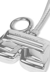 Zilveren sleutelhanger in de vorm van een short met een glanzende afwerking. Kenmerkt zich door de gravure "KARL LAGERFELD" aan de voorkant en een getextureerde band.