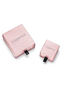 Två rosa presentförpackningar med gyllene hjärtmönster; en stor med svart banddragtab och en mindre bredvid, båda med en logotyp.