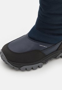 Bota impermeável azul escura com parte superior em couro liso, cano em tecido texturizado e sola de borracha preta robusta. Apresenta a marca "AMPHIBIOX".
