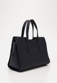Sac fourre-tout en cuir bleu marine avec une finition texturée, une forme structurée, des poignées doubles et une poche zippée sur le côté. Base robuste avec des coutures soignées.