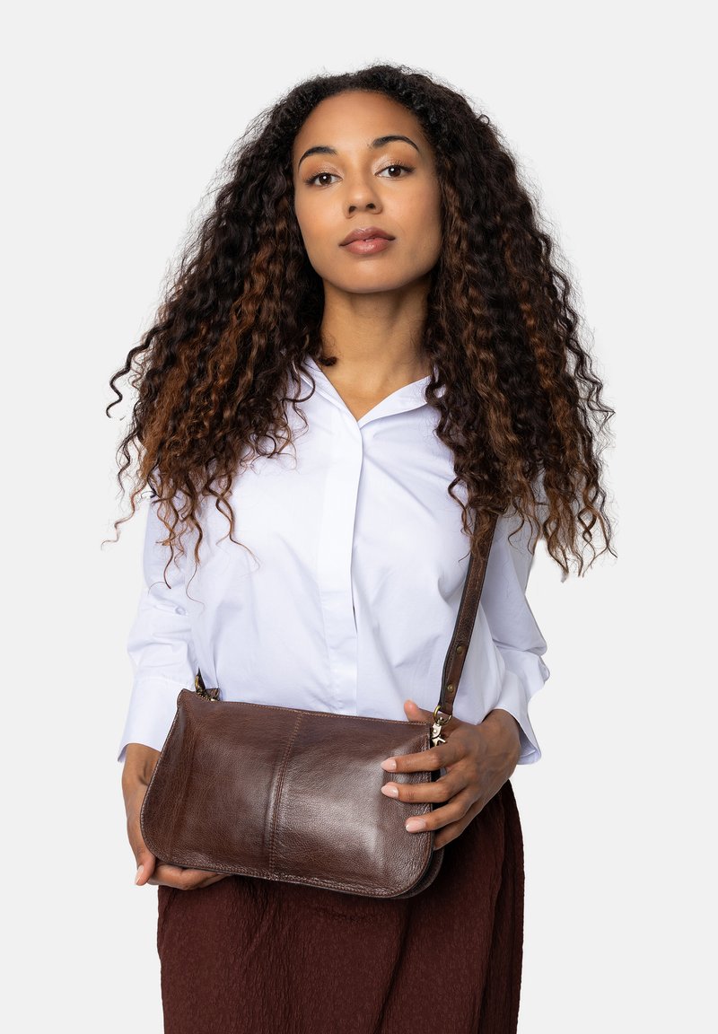 Borsa a tracolla in pelle marrone con una texture liscia, forma curva e tracolla staccabile. Caratterizzata da accessori in argento e dettagli di cucitura minimi.