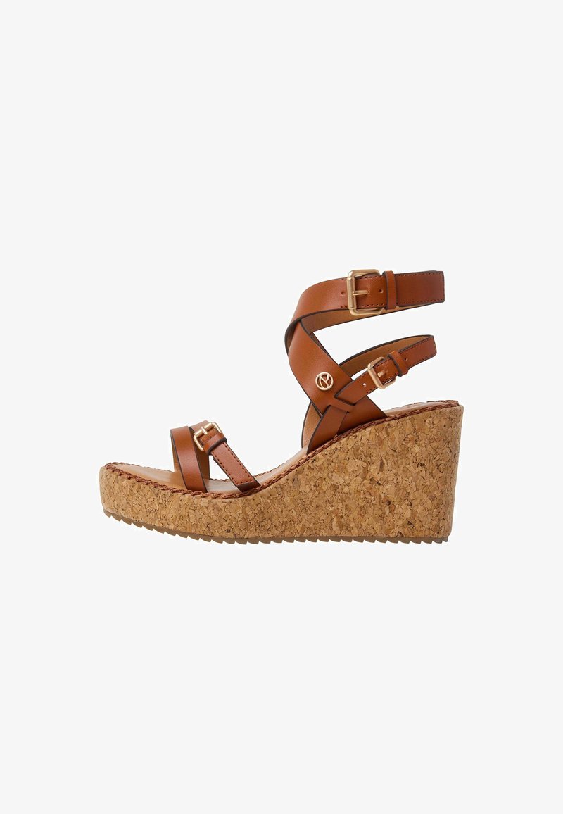 Pruunist nahast tõukesandaalid korgist platvormi, kahe pahkluu rihmaga ja kuldse värvusega kinnitustega. Omab tekstureeritud tallat, et tagada haakuvus.