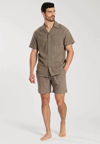 Chemise à manches courtes, à boutons, et shorts assortis en tissu texturé beige clair, comportant une poche poitrine et une coupe décontractée.