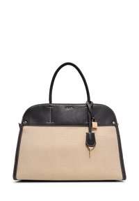 Beige canvas handbag with black leather accents, rounded top, double handles, and gold-tone hardware. Contrast stitching highlights the design.