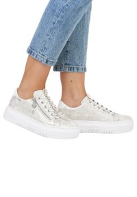 Baskets argentées métalliques avec une finition texturée, semelle en caoutchouc blanche et détail de zip sur le côté. Associées à un jean cropped bleu clair.