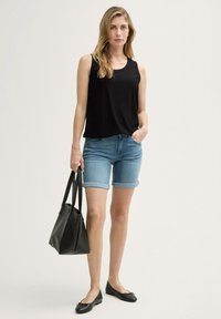Sort ærmeløs top med tekstureret mønster, lyseblå denimshorts med opfoldede kanter, sorte flade sko og en sort tote bag.