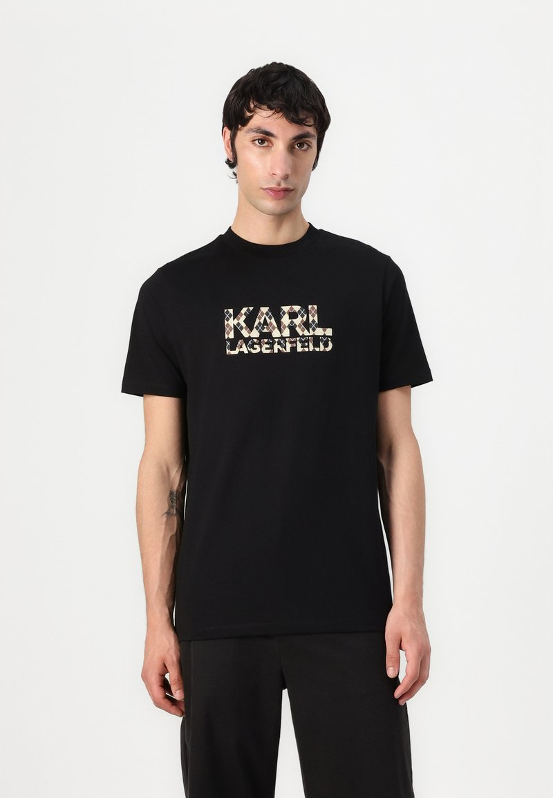 Juodas medvilnės marškinėlis su grafine logo "KARL LAGERFELD" šviesiai bežinės ir rudos spalvų raštu. Trumpomis rankovėmis, apykaklė suapvalinta.
