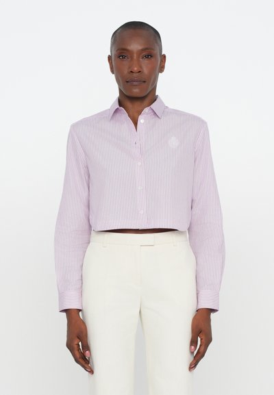 Korte, langmouwige shirt met verticale lavendelkleurige en witte strepen, knoopsluiting aan de voorkant, geborduurd logo op de borst, gecombineerd met witte broeken.