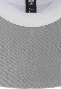 Casquette grise avec une visière plate et des coutures blanches. Le matériau semble être un tissu texturé. Étiquette intérieure visible au centre.