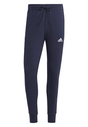Marineblauwe slim-fit Adidas joggingbroek met elastische tailleband, trekkoord, geribde enkels en wit Adidas-logo op de linker bovenbeen.