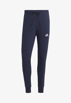 Pantalon de survêtement Adidas slim bleu marine avec taille élastique, cordon de serrage, poignets resserrés et logo Adidas blanc sur le haut de la cuisse gauche.