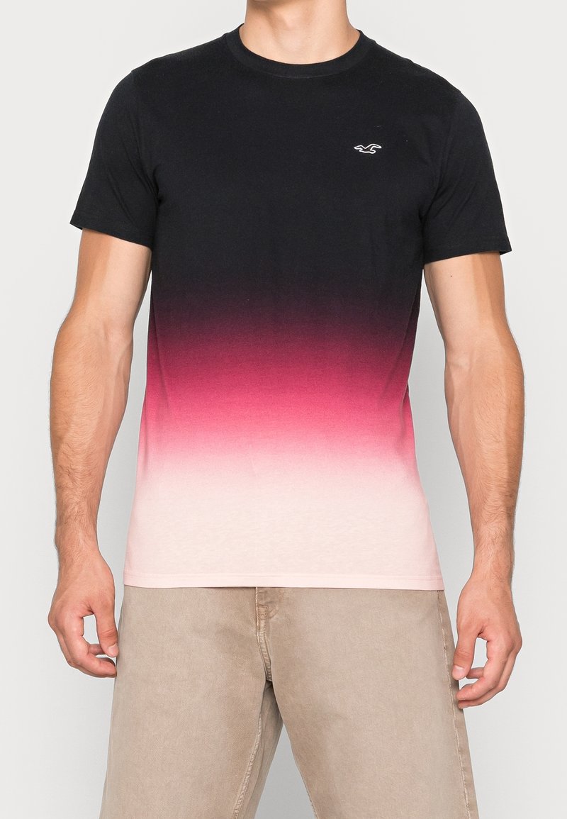 Tříčtvrteční tričko s krátkým rukávem v černé barvě, která přechází do růžové a bílé. Vyrobeno z bavlny s kulatým výstřihem a malým logem na levém prsu.