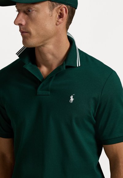 Polo de culoare verde închis cu un guler clasic, având un logo brodat alb pe piept și accente în dungi pe guler.
