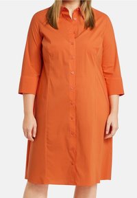 Abito arancione con bottoni, colletto, maniche a tre quarti e silhouette dritta. Realizzato in tessuto morbido con un colore uniforme.