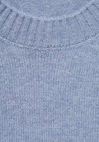 Light blue knitted wool sweater with ribbed crew neckline and soft, textured fabric.