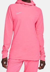 Sudadera de manga larga rosa hecha de tela suave, con un bolsillo frontal, capucha y el logo blanco de Nike en el lado izquierdo del pecho.