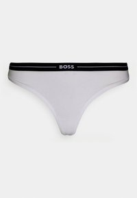 Biele tangá nohavičky vyrobené z hladkej tkaniny, s čiernym elastickým pásom so bielym logom "BOSS" a minimalistickým dizajnom.