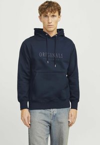 Marineblå hoodie lavet af sweatstof, med en frontlomme, snørehætte og "ORIGINALS JACK & JONES" trykt på brystet.
