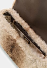 Borsa marrone con un morbido bordo in pelliccia sintetica color sabbia. Presenta una chiusura a zip e un rivestimento interno liscio, con in evidenza il logo del brand.