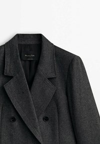 Cappotto doppio petto grigio in misto lana con rever a notched, bottoni neri e una fodera interna liscia, che presenta un design classico su misura.