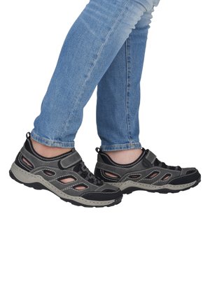 Black and gray athletic shoes with open mesh panels, rubber soles, and Velcro strap. Features contrasting stitching and a rounded toe design.