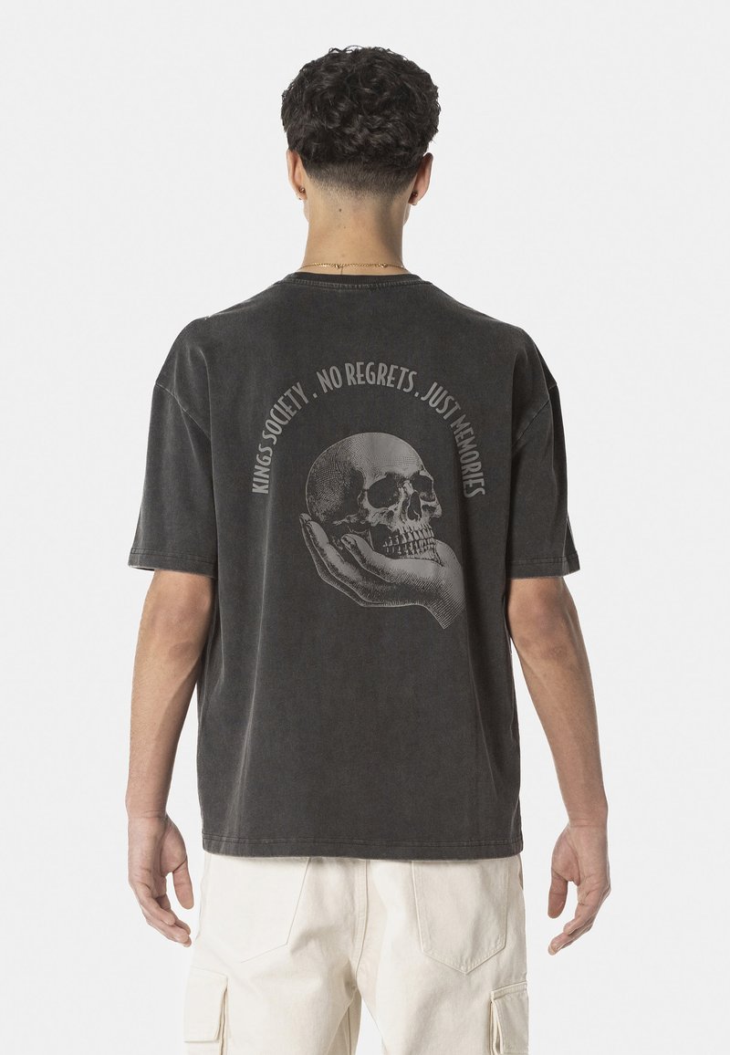 Black oversized T-shirt with a round neckline, featuring a graphic of a skull in a hand on the back and text, made of cotton fabric.