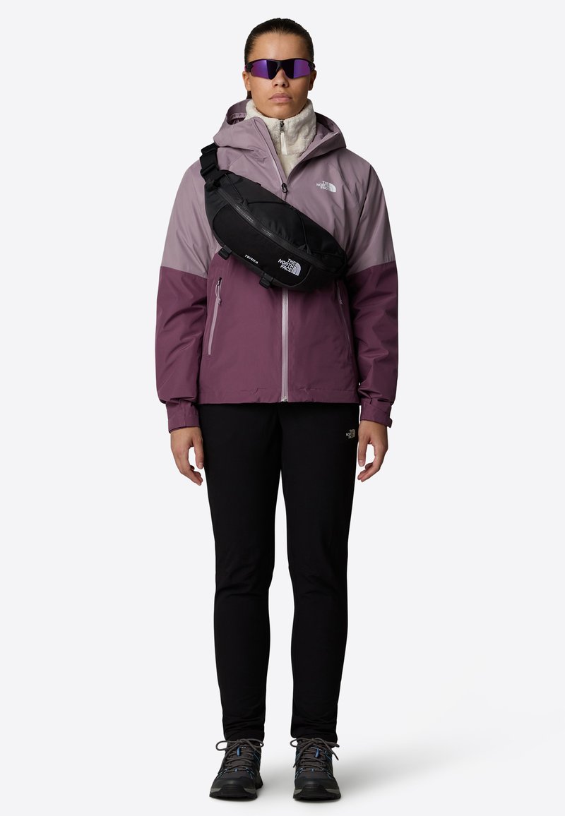 Hettegenser i lilla og grått over hvit fleece, svart hofteveske, svarte bukser, grå turstøvler og speilsolbriller. Uformell utendørsbekledning.