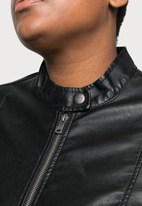 Černá kožená bunda s vysokým límcem, zipovým zapínáním a stříbrnými detaily. Hladká textura se švy podél okrajů.