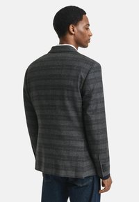 Grau kariertes Blazerjacke mit taillierter Passform, ausgestattet mit einem Revers, einem einzelnen Rückenschlitz und knöpfbaren Manschetten. Strukturierter Stoff mit glatter Oberfläche.