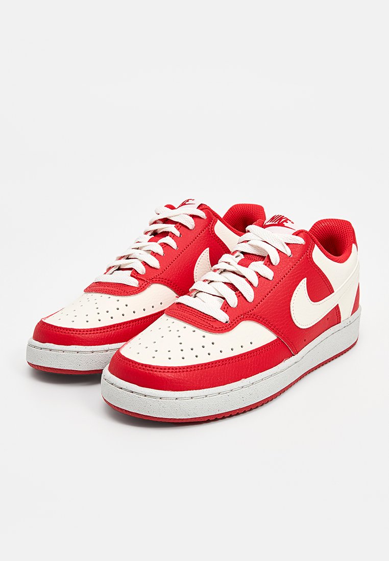 Baskets en cuir rouge et blanc avec un bout perforé, des lacets plats et une semelle en caoutchouc grise. Présente un logo prominent sur le côté.