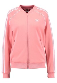 Ljust rosa zip-jacka med vita ränder på axlarna och ärmarna. Ribbad fåll och ärmslut; har sidofickor och logotyp på bröstet.