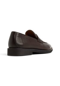 Bruine leren instap-schoen met een ronde neus en een lage zwarte rubberen zool, met een gladde textuur en minimale details.