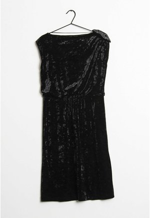 Černé sametové šaty bez rukávů se stahováním v pase, asymetrickým výstřihem a ozdobou na rameni zavěšené na černém ramínku.