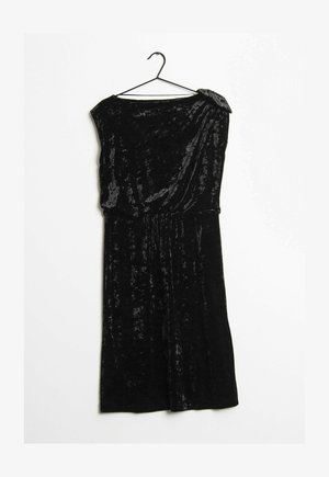 Czarna aksamitna sukienka bez rękawów z marszczonym stanem, asymetrycznym dekoltem i zdobieniem na ramieniu, wisząca na czarnym wieszaku.