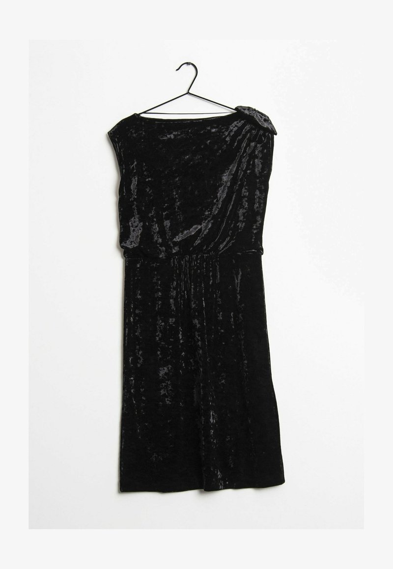 Robe sans manches en velours noir avec une taille froncée, un décolleté asymétrique et une décoration sur l'épaule, accrochée à un cintre noir.