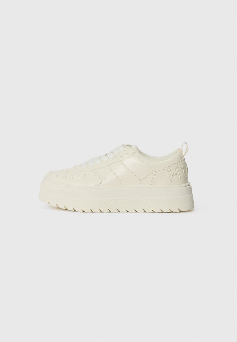 White leather sneaker with textured accents, thick sole, and prominent stitching, featuring a logo on the heel and a lace-up front.