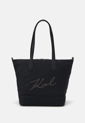 Black tote bag with dual handles and zipper closure, featuring raised script logo "Karl" on the front center.