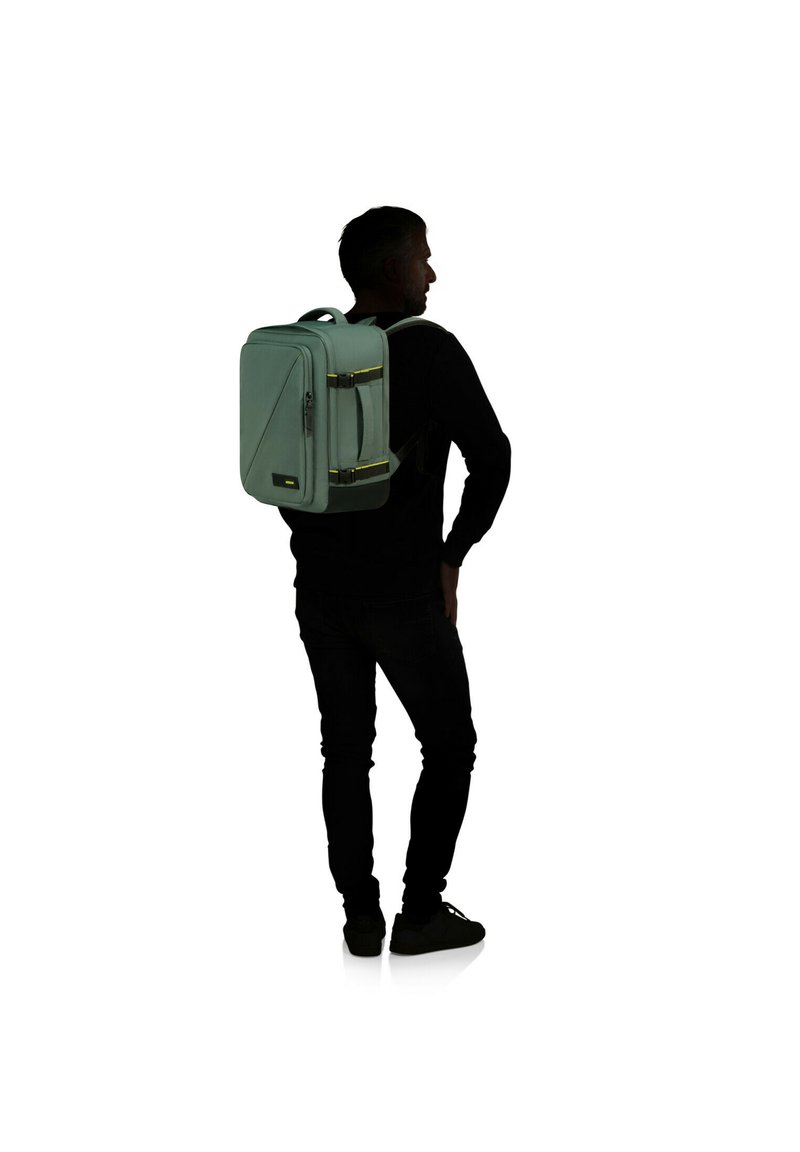 Mochila verde menta con forma rectangular, dos cremalleras frontales y detalles en negro. Cuenta con correas de hombro acolchadas.