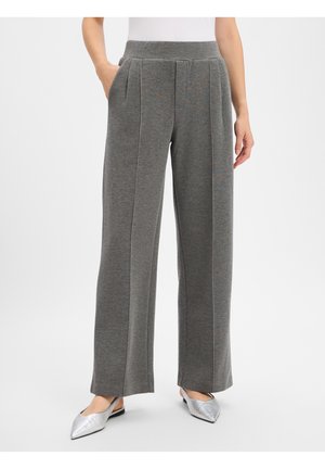 Grijze broek met wijde pijpen, voorplooien en zakken, gedragen door een persoon met zilveren puntige slingbackschoenen.