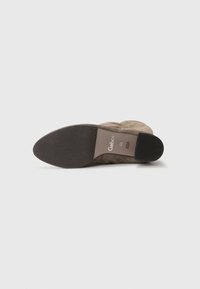 Botte Gabor avec une tige en daim marron et une semelle en caoutchouc plate. Caractérisée par un branding minimal sur le côté intérieur. Texture lisse, design à bout rond.