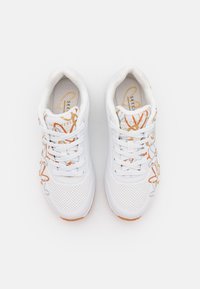 Sneakers atletici bianchi con accenti arancioni e grigi, design perforato e una soletta testurizzata. I lacci sono fissati in uno stile tradizionale.