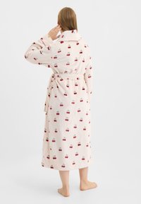 Bata de felpa color rosa claro con estampado de cerezas. Cuenta con cuello, mangas largas y cinturón a la cintura. Longitud hasta la mitad de la pantorrilla, textura suave.